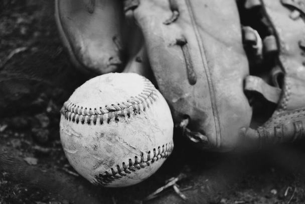 Бейсбол на полі з м'ячем і рукавичками в чорно-білому через рифлений паркан
. - Фото, зображення