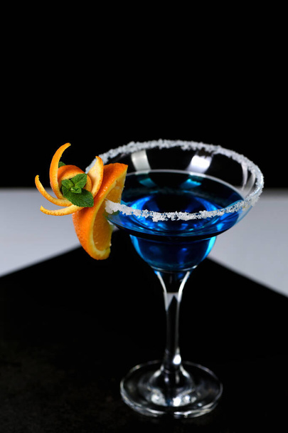 Décoration pour un cocktail d'orange et de menthe. Présentation élégante et originale. Martini Blue Curaçao sur fond noir - Photo, image
