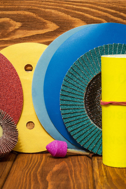 Big set of abrasive tools and multicolored sandpaper on wooden vintage background, wizard is used for grinding items - Photo, Image