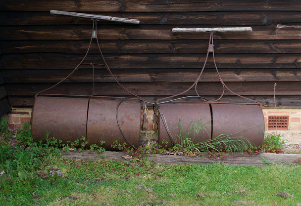 Deux rouleaux de jardin à l'ancienne contre une remise en bois
 - Photo, image