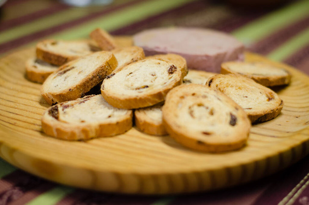 Pate board met rozijnenbroodjes. U kunt een houten plank met een stuk biologische paté en broodjes met rozijnen zien. - Foto, afbeelding