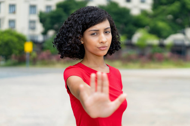 Brazilian young adult woman gesturing stop and social distancing outdoor in city - Fotó, kép