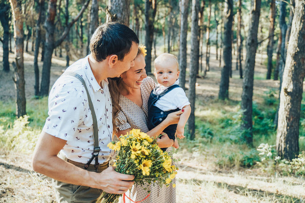 Lovely family walking in the summer forest. Happy parents enjoying fresh air and beautiful nature, holding hands, talking, smiling and laughing. Healthy lifestyle. Parents looking to sun and talking - Photo, Image