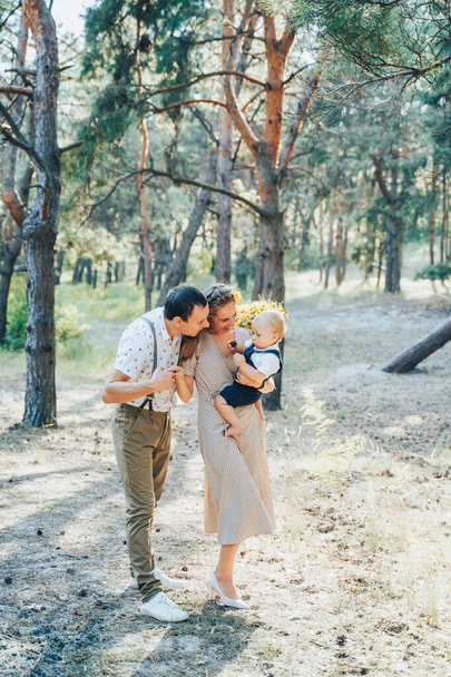 Lovely family walking in the summer forest. Happy parents enjoying fresh air and beautiful nature, holding hands, talking, smiling and laughing. Healthy lifestyle. Parents looking to sun and talking - Photo, Image