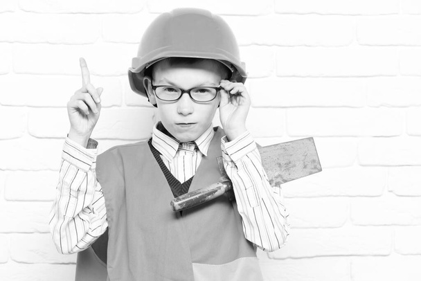 young cute builder boy on white brick wall background - 写真・画像