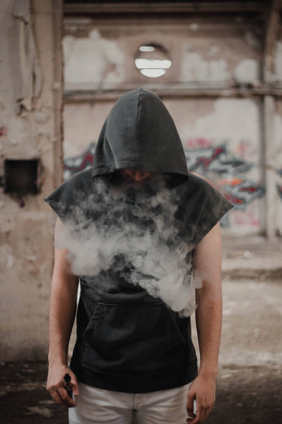 Jongen die rook uit elektronische sigaret verdrijft - Foto, afbeelding