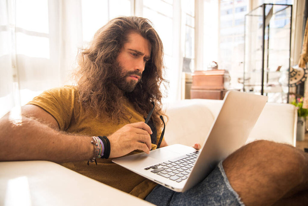 uomo con i capelli lunghi che lavora con il suo portatile in un ufficio
 - Foto, immagini