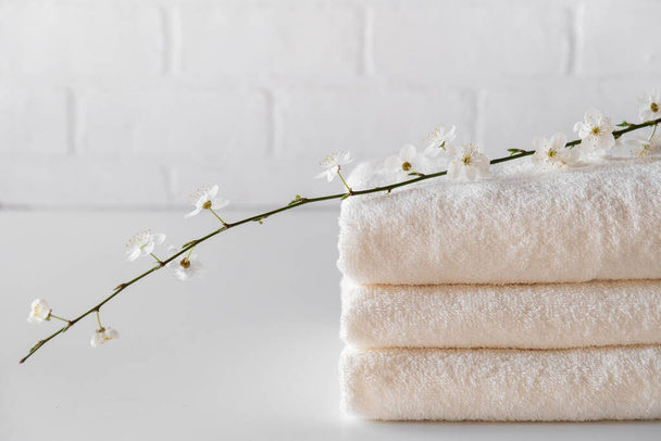  Montón de tres toallas de baño mullidas blancas con rama. Composición del spa Copiar espacio
 - Foto, imagen