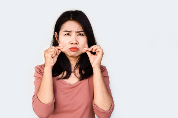 unhappy Asian woman hand pulling her fat skin on cheeks ,aging and overweight concept - Photo, image