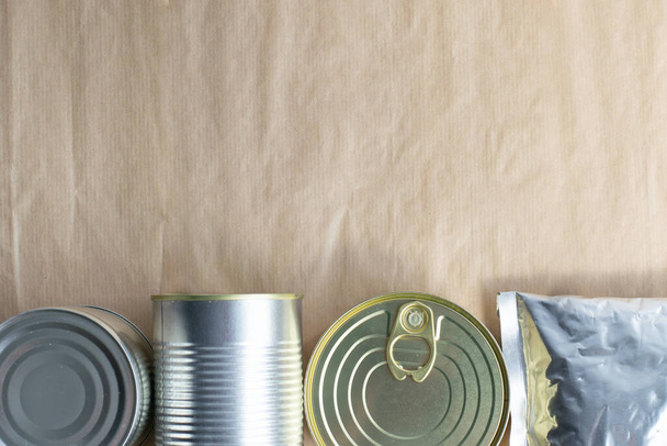 Canning metal cans of different sizes, metallized flexible bag for preservation on a craft background. A variety of packaging for canned food. Space for text. - Фото, зображення