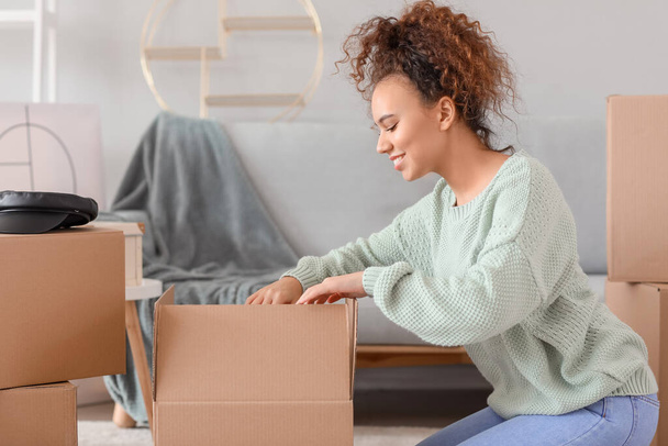 Young woman unpacking moving boxes in her new home - Photo, Image