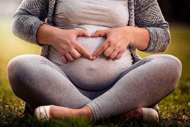 Femme enceinte montrant la forme du cœur sur son ventre
.  - Photo, image