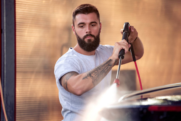 Young attractive man cleaning his car outdoors. - Photo, image