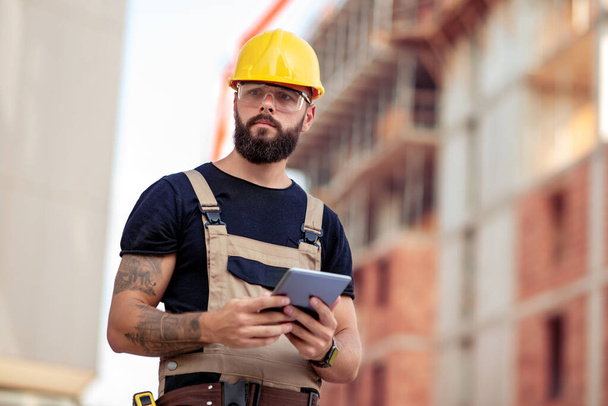 Ingeniero masculino en un sitio de construcción con una tableta. - Foto, Imagen