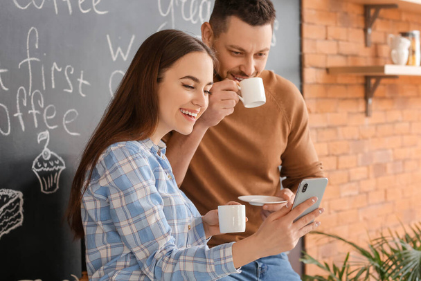 Коллеги с мобильным телефоном пьют кофе на кухне офиса
 - Фото, изображение