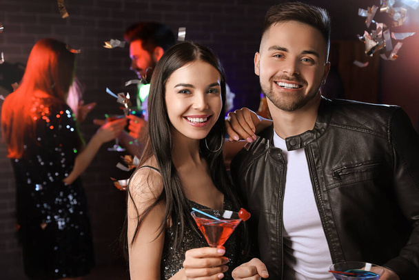 Happy young couple with cocktails in night club - Фото, изображение