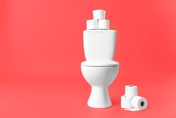 Toilet bowl with rolls of paper on color background - Foto, afbeelding