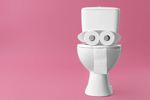 Toiletpot met rollen papier op kleur achtergrond - Foto, afbeelding