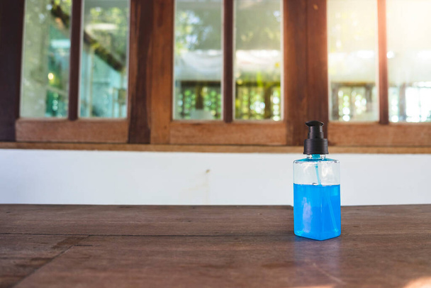 Zbliżenie 70% niebieskiego żelu z alkoholu etylowego w plastikowej butelce na drewnianym biurku w celu ochrony przed koronawirusami   - Zdjęcie, obraz