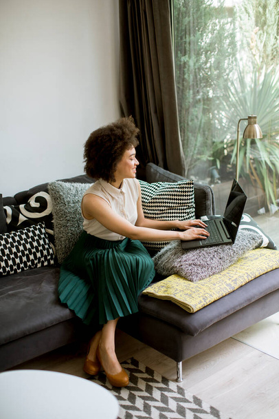 Привлекательная молодая кудрявая женщина, работающая дома на ноутбуке
 - Фото, изображение