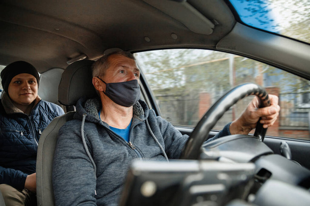έννοια της προστασίας της υγείας, της ασφάλειας και της πανδημίας - αρσενικό οδηγό ταξί φορώντας μάσκα προστασίας του προσώπου αυτοκίνητο οδήγησης με επιβάτη - Φωτογραφία, εικόνα