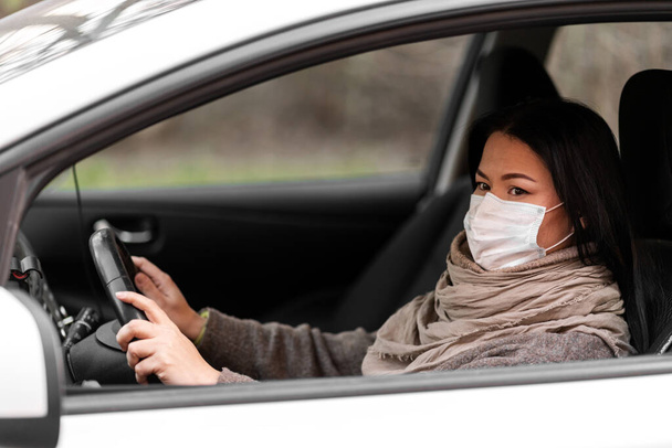 Ochrona przed wirusem. Kobieta prowadzi samochód w masce medycznej - Zdjęcie, obraz