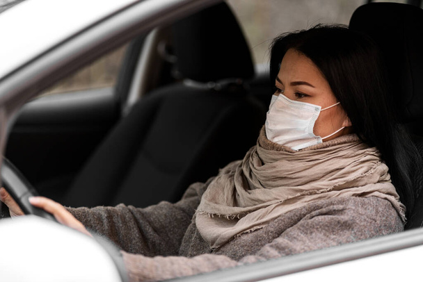 Egy nő autóvédő maszkot vezet. Egészségügy, vírusvédelem. Taxisofőr nő maszkban - Fotó, kép