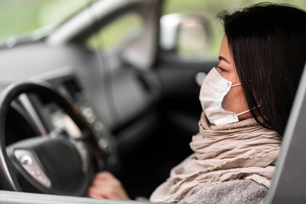 Mujer conduciendo coche con máscara médica. Protección contra el virus
. - Foto, imagen