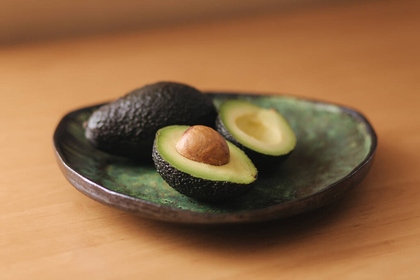 Fresh sliced avocado on green plate. Vegetarian food concept - Photo, Image