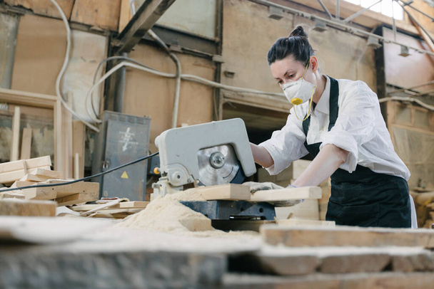 Confident woman working as carpenter in her own woodshop with sawmill - Foto, imagen