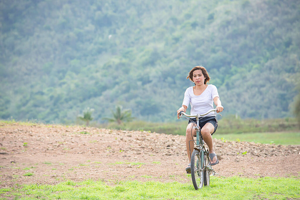 Asyalı kadınlar arka planda bisiklet sürüyor Dağlarda. - Fotoğraf, Görsel