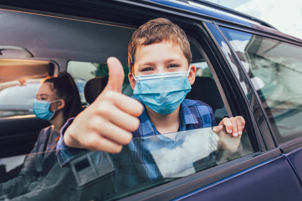 Dzieciaki noszą maski antywirusowe i używają cyfrowych tabletek w samochodzie. Dzieci podróżują samochodem podczas epidemii koronawirusa - Zdjęcie, obraz