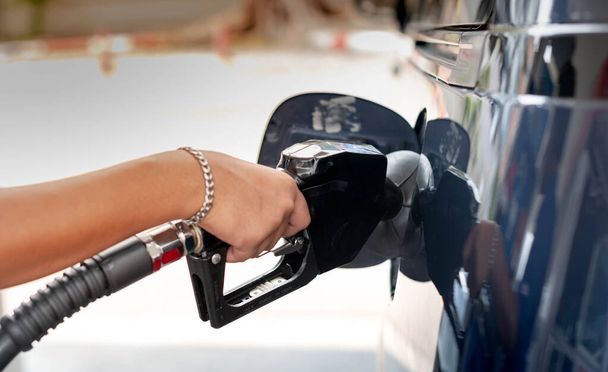 Männliche Hand tankt Benzin in Auto, das an Tankstelle mit Benzin gefüllt wird. - Foto, Bild