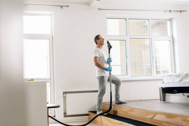 selective focus of happy man holding vacuum cleaner  - Photo, Image