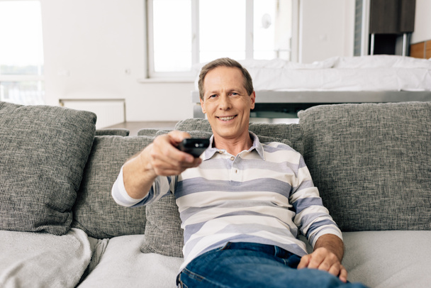 selective focus of cheerful man holding remote controller at home   - Foto, Bild