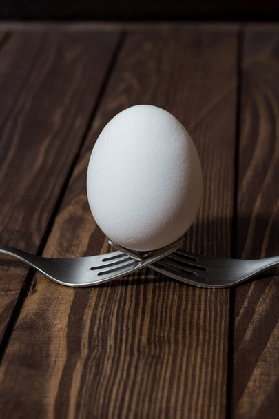 egg on a dark background. white egg on a dark wooden background - 写真・画像