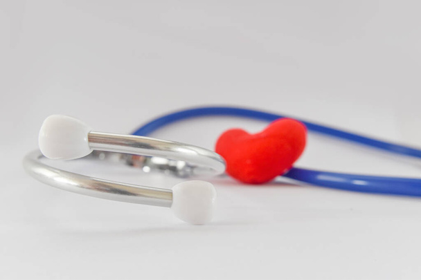 Estetoscopio azul médico y corazón rojo sobre fondo blanco. Idea para enfermedad de diagnóstico médico
. - Foto, imagen