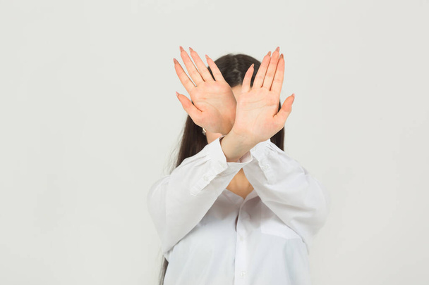 beautiful young woman in a white shirt on a white background with hand gesture - Φωτογραφία, εικόνα