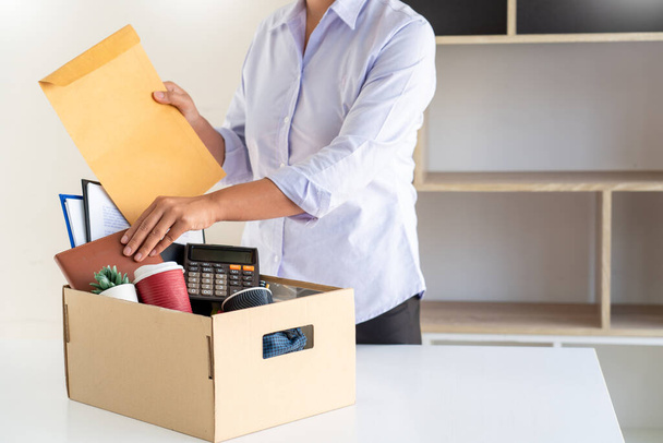 Geschäftsfrau, die von ihrem Job zurücktritt, hält Kisten und packt persönliche Sachen ein. Kündigungskonzept beschließen und Arbeit in Zukunft verändern - Foto, Bild