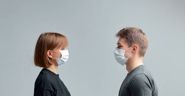 Cute boy and girl in medical masks keep their distance during the quarantine period and the global pandemic. - Fotó, kép