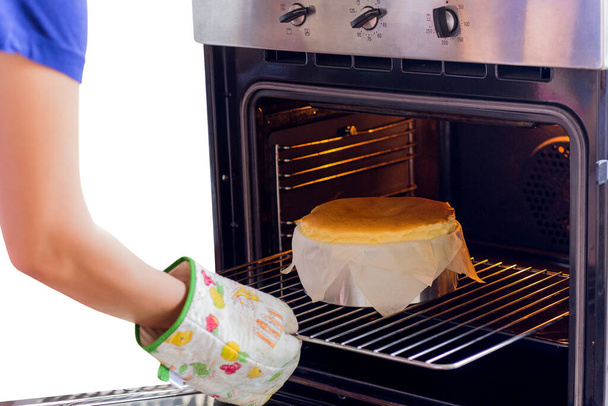 Frau holt verbrannten Käsekuchen isoliert aus dem Ofen - Foto, Bild