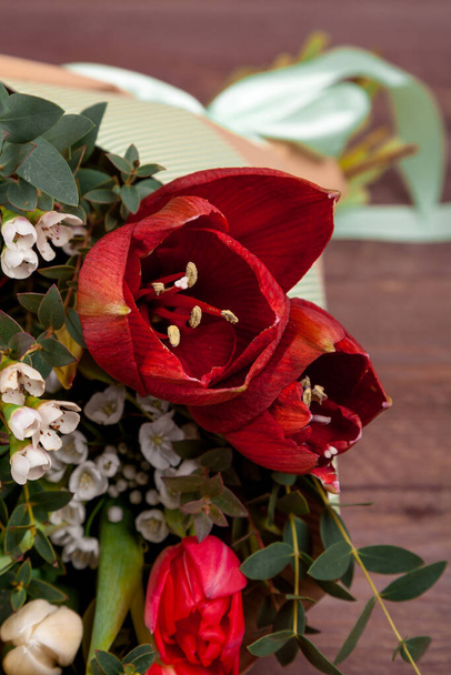 a bouquet of flowers with tulips, chamelaucium, Amaryllis and eucalyptus on wooden table. high quality - Foto, afbeelding