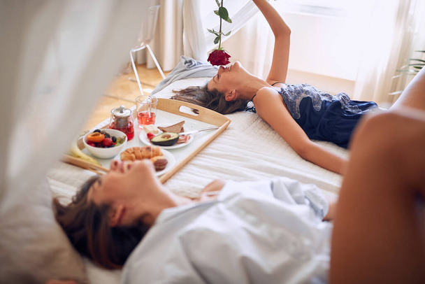 Romantic happy lesbian in bed with rose - Foto, Imagen