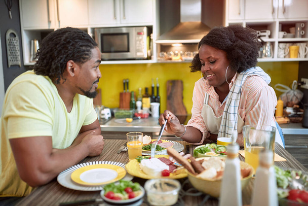 young afro-american couple enjoying breakfast together. togetherness, joy, talk, sharing meal - Fotó, kép