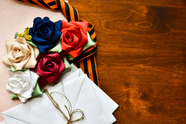 9 mei vakantie, enveloppen met brieven, bloemen, St. George lint op een houten tafel, bovenaanzicht. plaats voor tekst - Foto, afbeelding