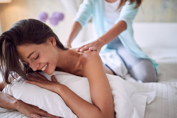Smliling girl   lying on bed and enjoying at beautiful massage. - Photo, image
