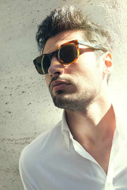 Gyönyörű és elbűvölő férfi napszemüveggel, a szabadban. Erős fény hátulról.. - Fotó, kép