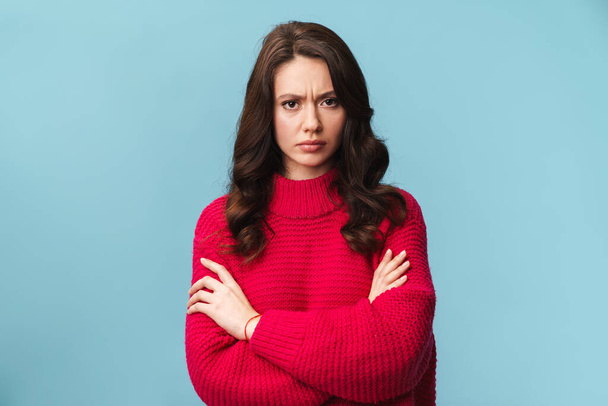 Photo of caucasian confused displeased woman frowning and standing with arms crossed isolated over blue background - Photo, image