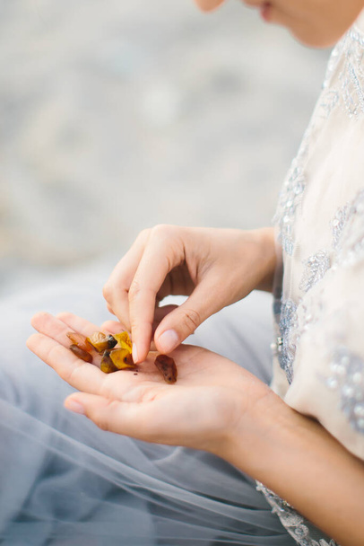 Amber in handen. Een vrouw houdt stukjes amber in haar handpalmen en onderzoekt ze.. - Foto, afbeelding