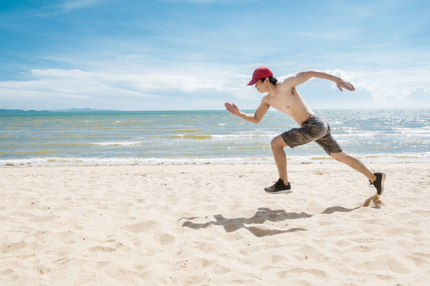 L'uomo muscolare sta correndo sulla spiaggia
  - Foto, immagini